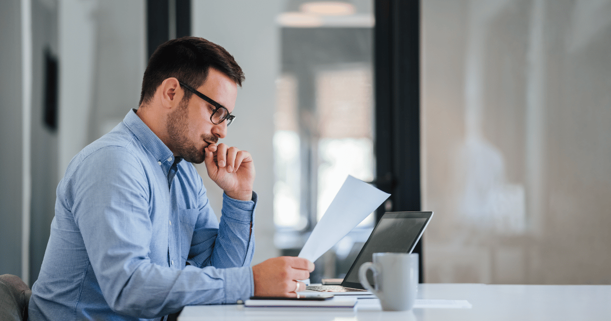 man reviewing work at desk with laptop