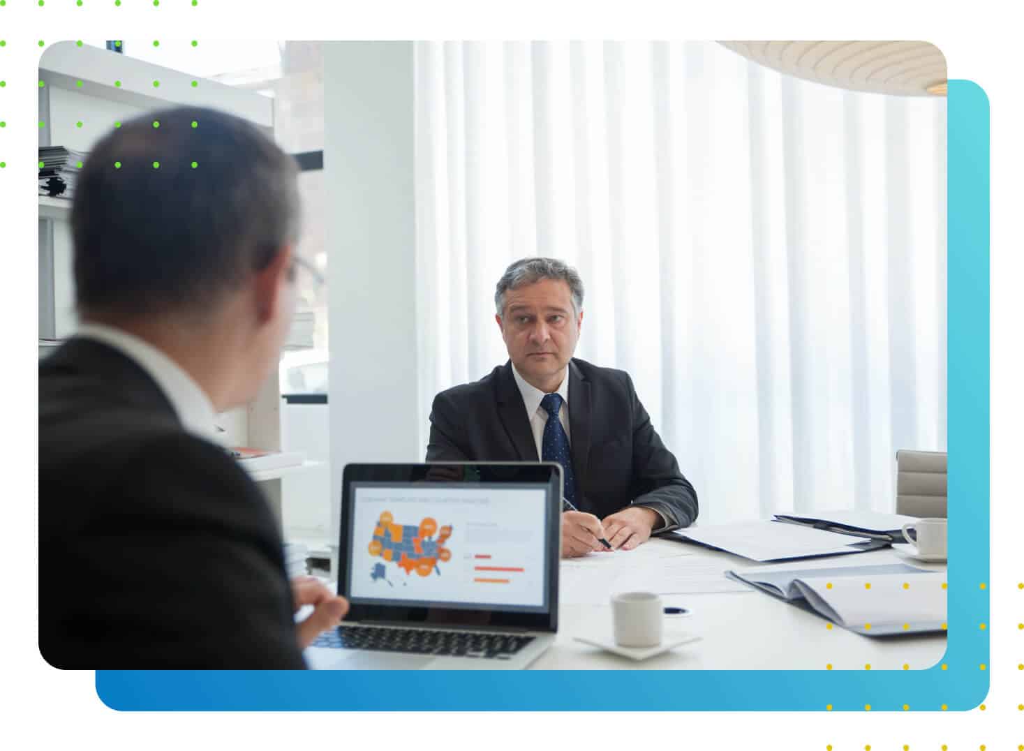 A man in suit in front of another with laptop in between