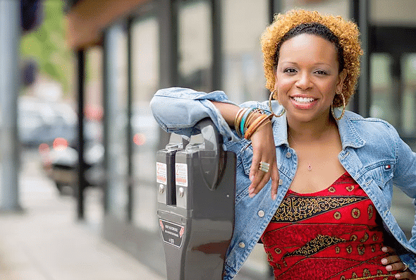 LeanLaw Lozelle Mathai smiling and leaning against parking meter
