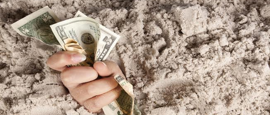 LeanLaw Hand sticking out of sand holding dollar bills tightly